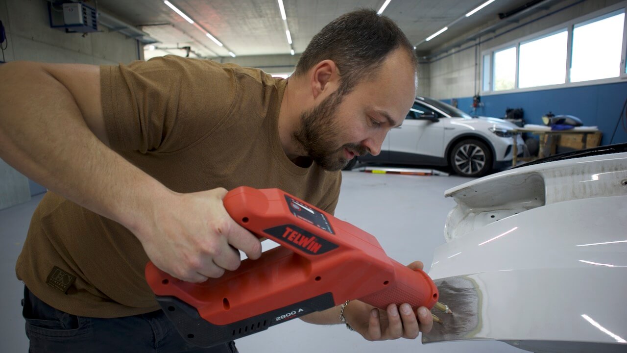 Mitarbeiter bei Ausbeularbeiten an einer Fahrzeugkarosserie zur präzisen Wiederherstellung der ursprünglichen Form.