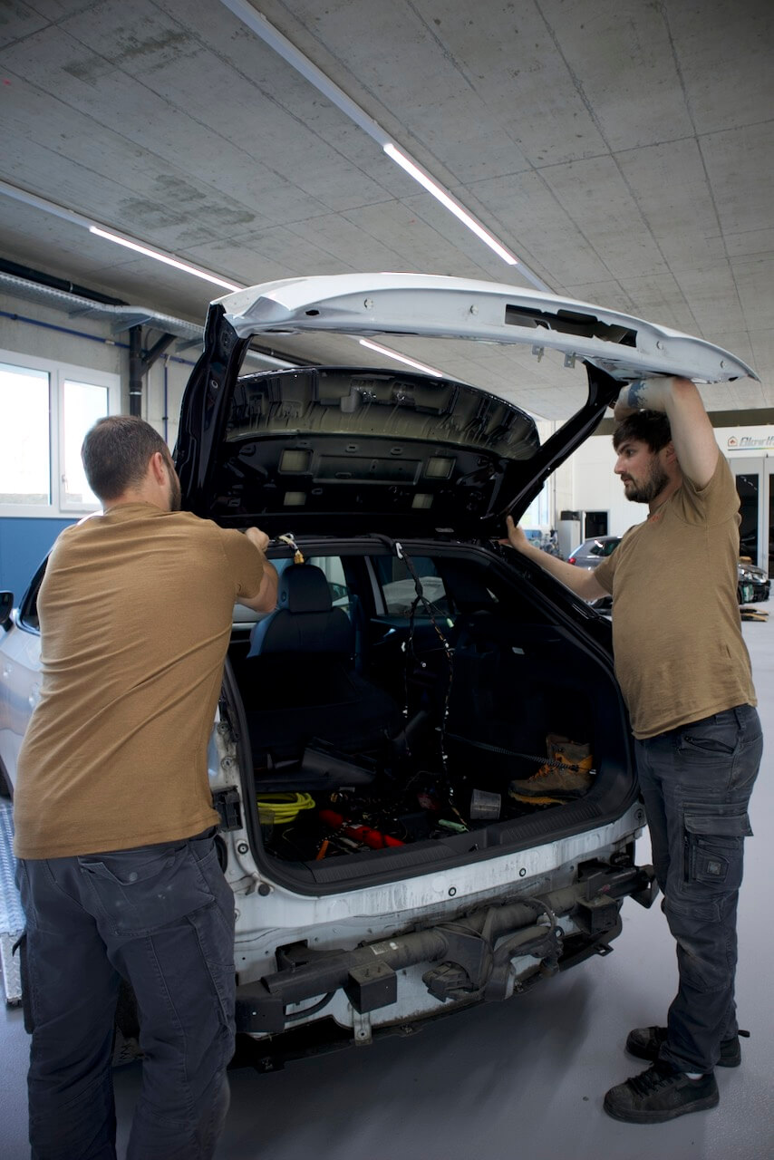 Mitarbeiter bei der Demontage einer Heckklappe zur Vorbereitung von Reparatur- oder Lackierarbeiten.